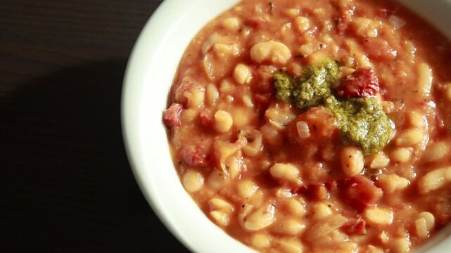 Serving Delicious Bean Stew with Sun Dried Tomatoes in Bowl Close Up