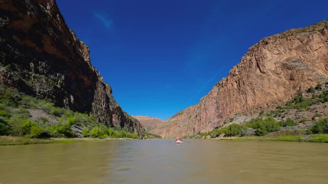 Yampa River flowing between steep canyon walls beneath clear blue desert skies, backcountry pack rafting experience