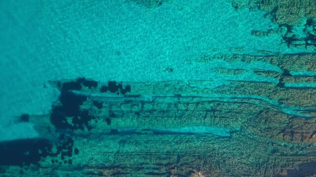 Underwater rock formation near coast. Aerial birdseye descending