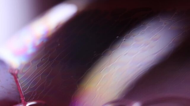 Deep maroon fluid macro with glowing soft highlight and micro lattice. Atmospheric horizontal macro footage of a dark wine and violet liquid surface.