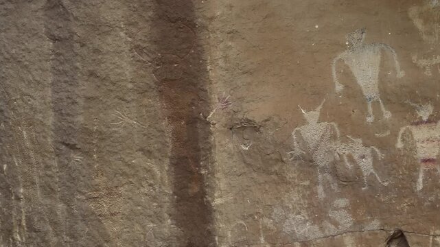Pictograph panel on sandstone cliff at heritage site, streak of water discolors rock above petrogylph carving