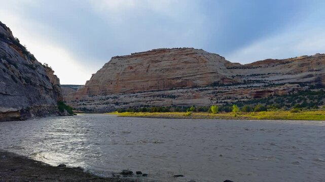 Harding Hole backcountry camping overlook spot, calm river bordered by rugged canyon hills and layered rock formations, medium static