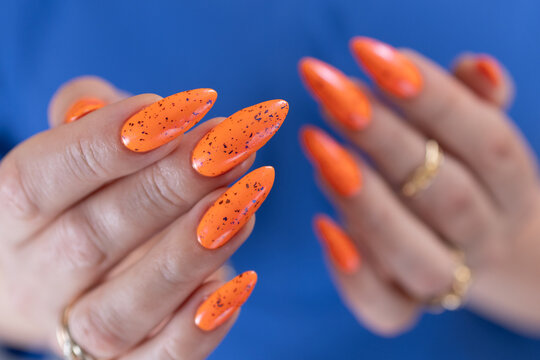 Female beautiful hand with long nails and a bright orange nail polish