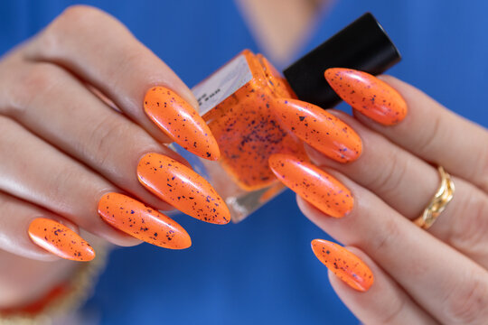Female beautiful hand with long nails and a bright orange nail polish