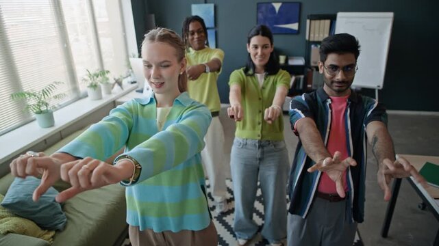 From above of multiethnic young adult colleagues doing hand stretching exercises in contemporary office. Video is perfect for corporate wellness programs and workplace health campaigns