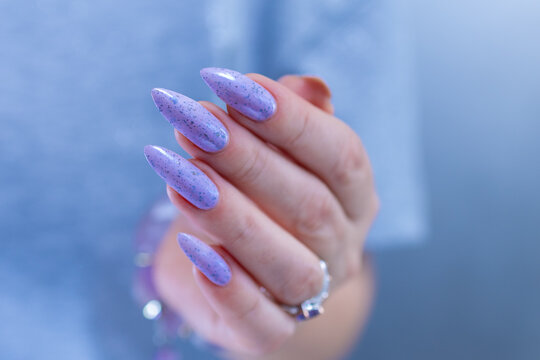 Woman hand with long nails manicure and light lilac, blue and pink nail polish