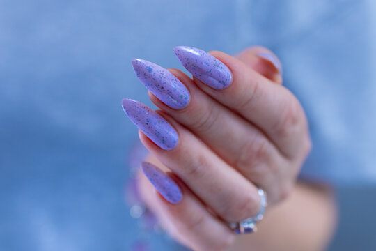 Woman hand with long nails manicure and light lilac, blue and pink nail polish