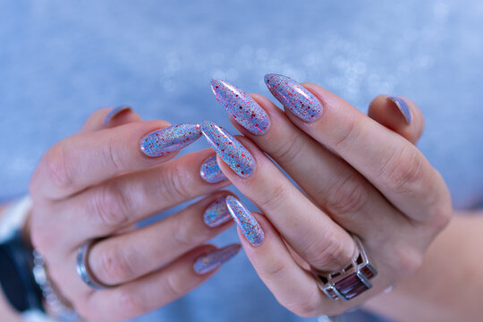 Woman hand with long nails manicure and light lilac, blue and pink nail polish