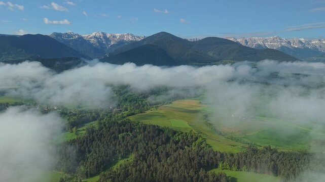 Snow capped Pyrenees mountains above misty valley and forests in Catalonia