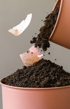 Food scraps and paper waste falling into a potting soil container for composting