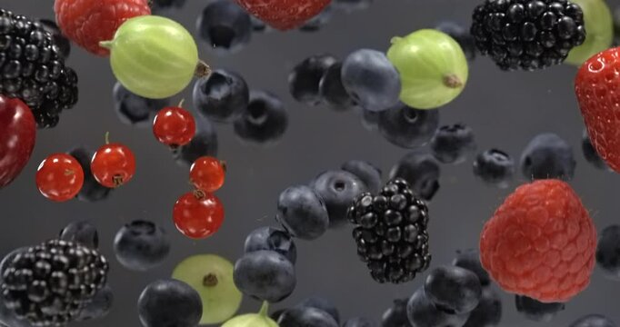 Mixed fresh berries floating in super slow motion on black background