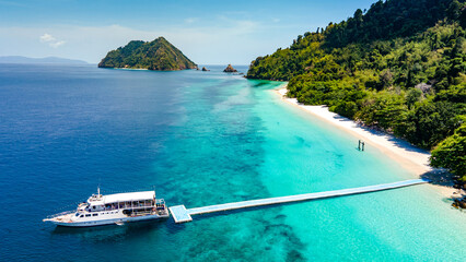 Aerial drone view of tropical landscape over Madam Beach of Nyaung Oo Phee Island with tour boat anchoring on the floating dock in the Mergui Archipelago, Myanmar. Beautiful Andaman sea in Burma © zephyr_p