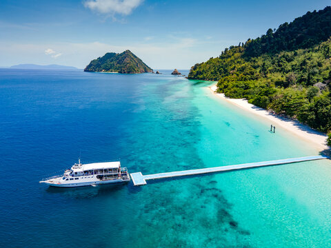 Aerial drone view of tropical landscape over Madam Beach of Nyaung Oo Phee Island with tour boat anchoring on the floating dock in the Mergui Archipelago, Myanmar. Beautiful Andaman sea in Burma