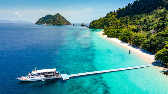 Aerial drone view of tropical landscape over Madam Beach of Nyaung Oo Phee Island with tour boat anchoring on the floating dock in the Mergui Archipelago, Myanmar. Beautiful Andaman sea in Burma