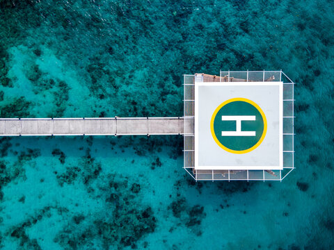Aerial view of helipad over the sea. Helicopter parking platform station linked to the land by long concrete bridge over turquoise water of Andaman sea at Nyaung Oo Phee island in Burma or Myanmar.