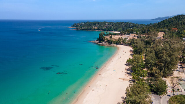 Aerial top view of Surin beach in Phuket, Thailand. Turquoise waves reach the Andaman sea coastline while tourists relaxing on the beach. Travel attraction for summer vacation