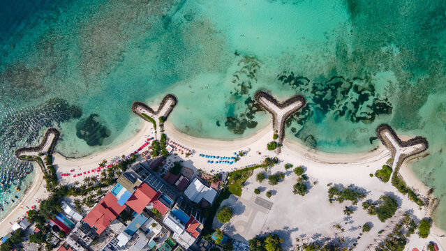 Aerial drone view of beachfront hotels and private beach at Maafushi island in Kaafu Atoll, Maldives.