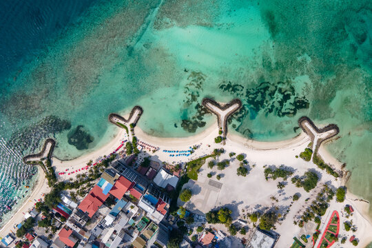 Aerial drone view of beachfront hotels and private beach at Maafushi island in Kaafu Atoll, Maldives.
