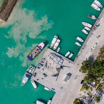 Aerial view of tour boats and logistic boats parking over turquoise water in the jetty at Maafushi island. Nautical vessel transportation system for travel and shipping industry in Maldives