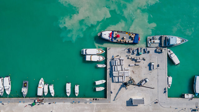 Aerial view of tour boats and logistic boats parking over turquoise water in the jetty at Maafushi island. Nautical vessel transportation system for travel and shipping industry in Maldives