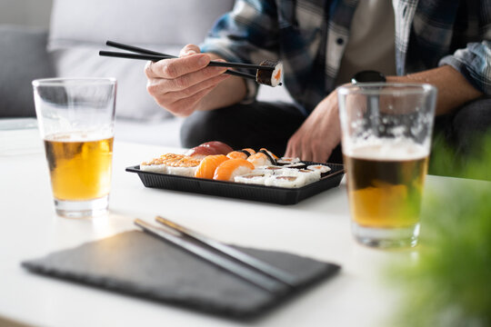 Man eating sushi with chopsticks at home
