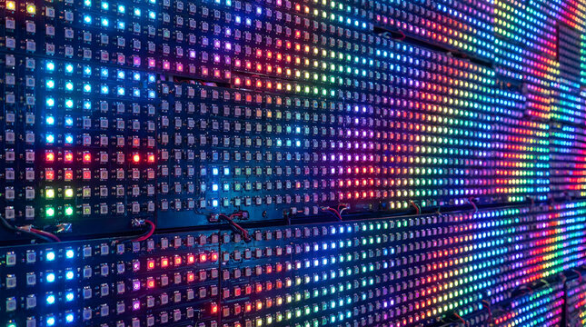 Abstract background featuring dense array of illuminated multicolor square light emitting diodes.