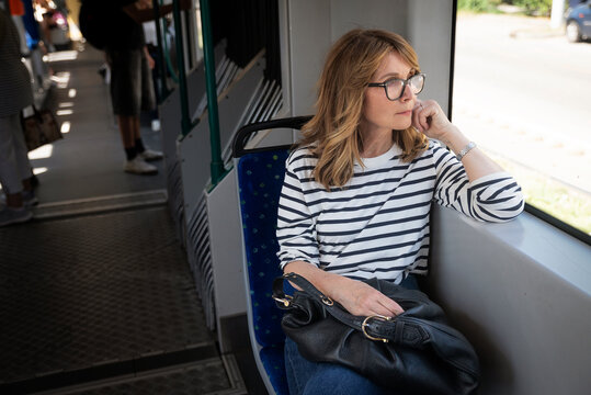 Smiling mid-aged woman on her way to home sitting in the tram