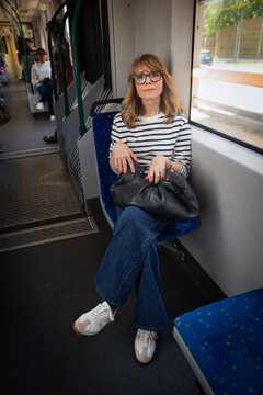 Smiling mid-aged woman on her way to home sitting in the tram by the window