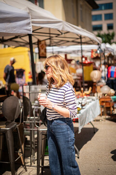 Blond haired mature woman walking at the flea market in an european city