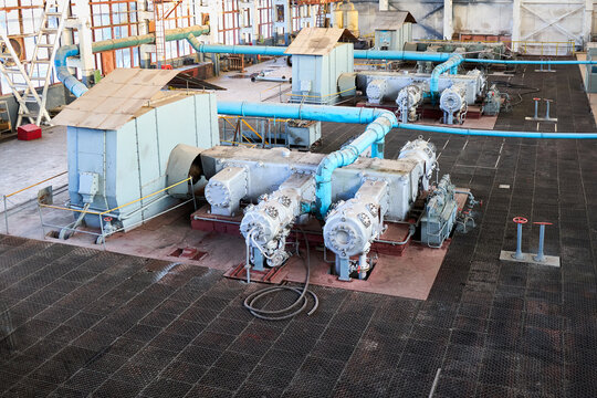 Interior of synthesis gas compressor for methanol production. Large blue pipes and grey metal machinery in industrial plant. Soviet engineering equipment for chemical processing and energy.