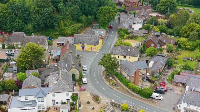 Godshill High Street drone ascent revealing thatched rooftops, quaint village houses, winding road and gardens in rural Isle of Wight, England. Charming countryside travel atmosphere.