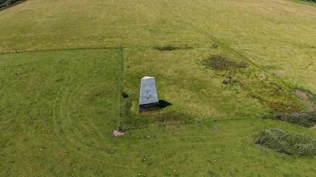 Ashey Down Sea Mark beacon flyover as a drone passes the navigation marker, then tilts up to reveal rolling fields, hedgerows, trees and the distant horizon in rural Isle of Wight, UK.