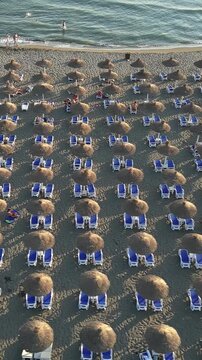 High angle view of the sandy velika plaza beach in montenegro. Thatched cabanas and palm trees line the shore of the adriatic sea