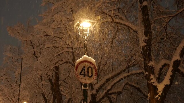 Speed Limit 40 Traffic Sign at Night During Snowfall, Winter Road Conditions and Driving Safety Warning