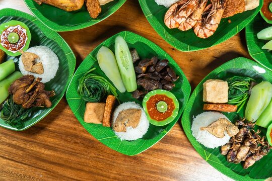 Savory Indonesian Fare: A spread of authentic Indonesian dishes, including rice, tofu, vegetables, and grilled meats, served on banana leaf plates.