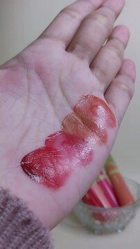 Showing palm skin filled with various lip tint colors. Beauty makeup product presentation, color swatch collection for cosmetic branding.