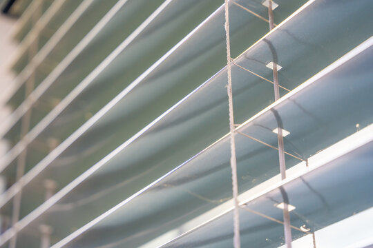 Close up of aluminum window blinds with tilt mechanism and slats. Sunlight regulation and privacy protection concept for modern buildings