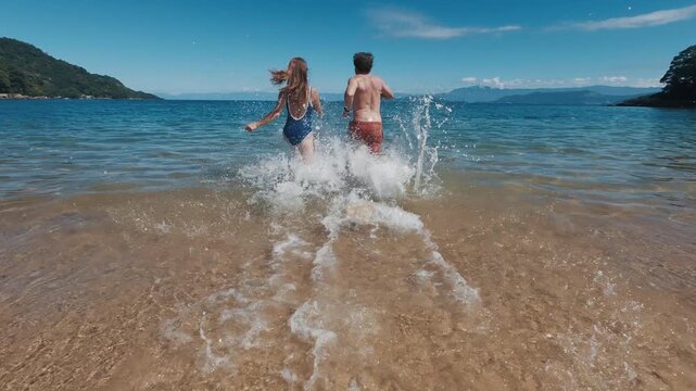 Young couple of man and woman run into the tropical sea