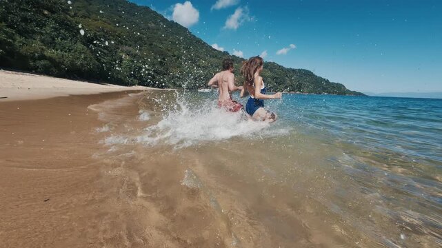 Young couple of man and woman run into the tropical sea