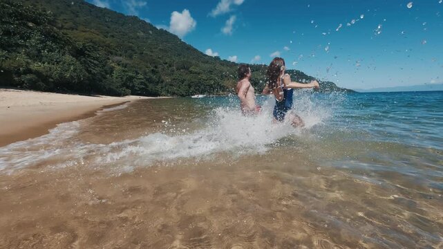 Young couple of man and woman run into the tropical sea