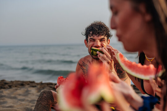 Friends enjoying watermelon on beach during summer vacation