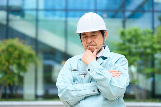 悩む作業着を着たアジア人男性