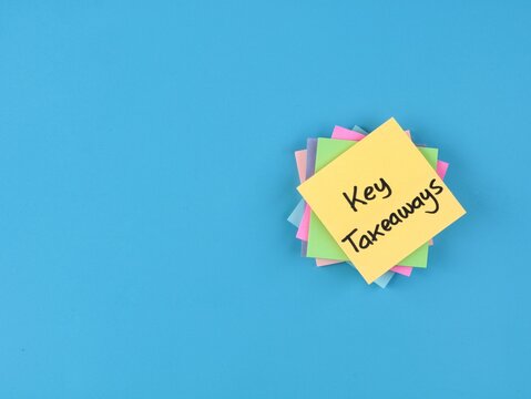 Key takeaways text handwritten on colorful adhesive notes on blue background with copy space. Ideal for business concepts, summaries, learning points, workshops, and presentation highlight