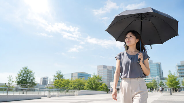 Woman Holding a Black Parasol on a Sunny Urban Walkway