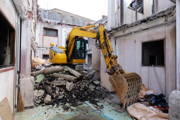 bulldozer demolishing an old abandoned building at a construction site in Japan. Heavy machinery breaking concrete structures with dust, debris and rubble during urban redevelopment. Realistic view of © Андрий Мищак