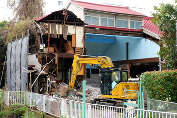 bulldozer demolishing an old abandoned building at a construction site in Japan. Heavy machinery breaking concrete structures with dust, debris and rubble during urban redevelopment. Realistic view of © Андрий Мищак