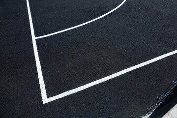 Fototapeta premium Basketball court lines are marked on a black surface showing a clear outline of the court area
