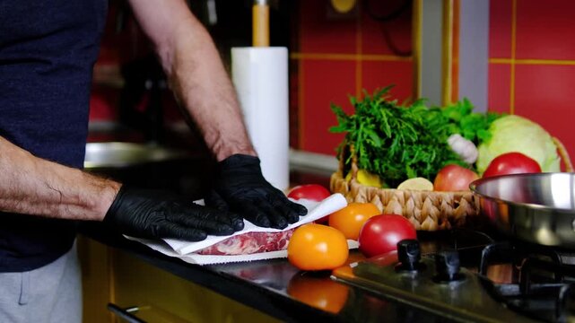 A chef gently presses a white paper towel against the beef to absorb excess moisture before frying. Dry meat helps create a crisp golden crust during cooking.