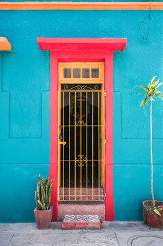 Colorful turquoise facade with a red and yellow door and potted plants, Olinda, Pernambuco, Brazil