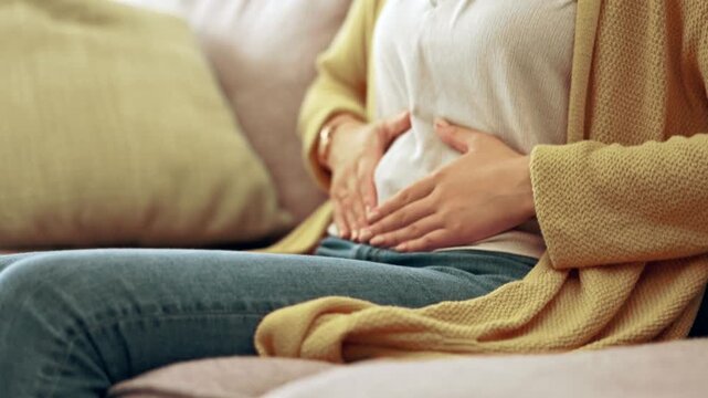 Woman holding her stomach due to abdominal pain, digestive discomfort, or gastrointestinal problem.